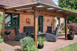 A covered patio with outdoor furniture, a brick building, and potted plants. - Holiday Home 'Ferienhaus Thomas' with Shared Terrace, Shared Garden and Wi-Fi (Colnrade)
