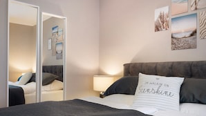Un dormitorio con cama, mesita de noche, espejo y decoración en la pared.