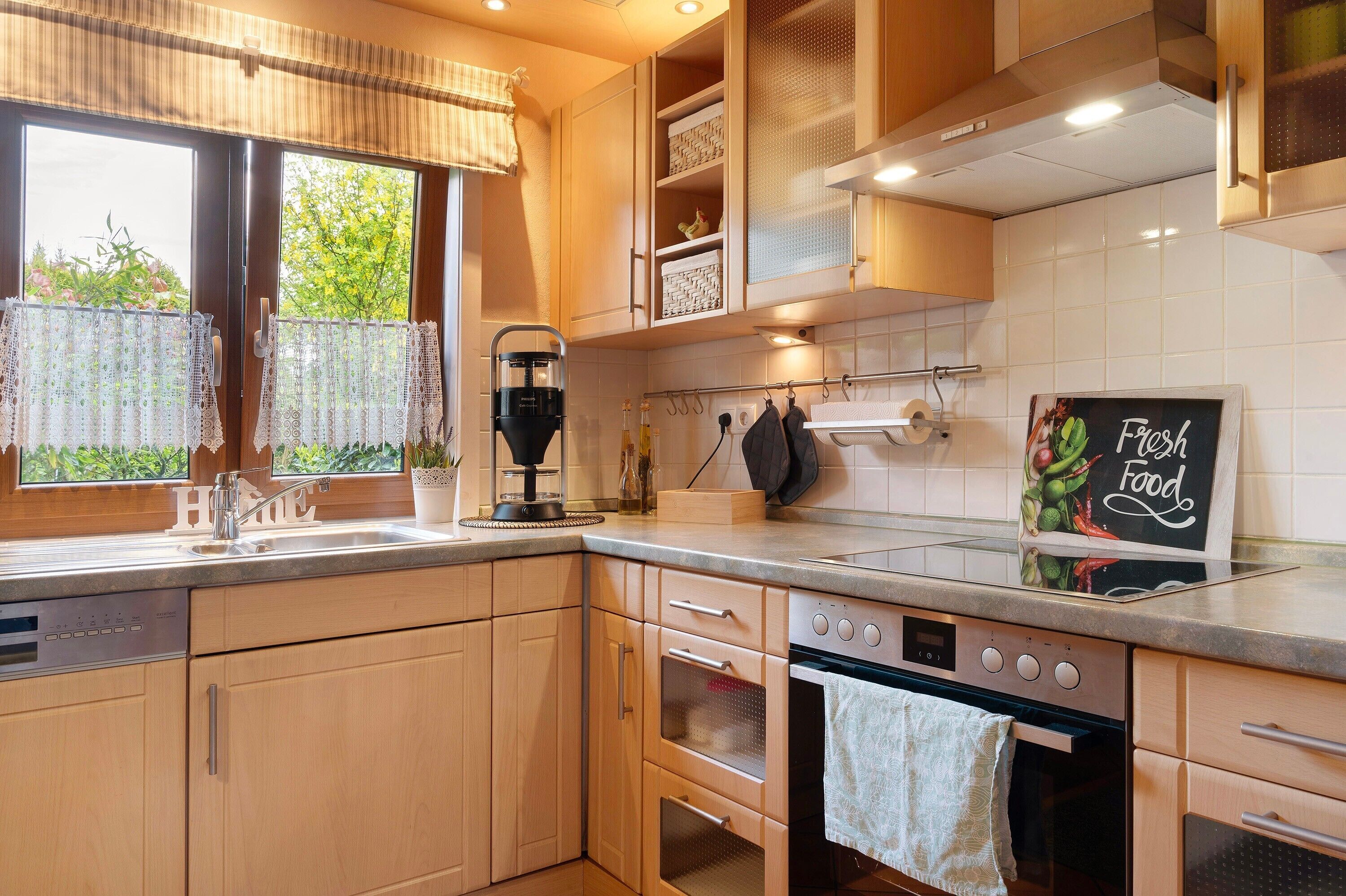 Una cocina con armarios de madera, horno empotrado y un cartel en la pizarra.