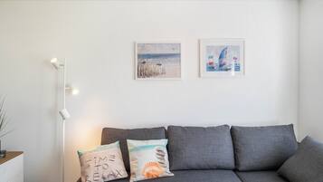 Ein modernes Wohnzimmer mit einem grauen Sofa, zwei Wandgemälden und einer Stehlampe.