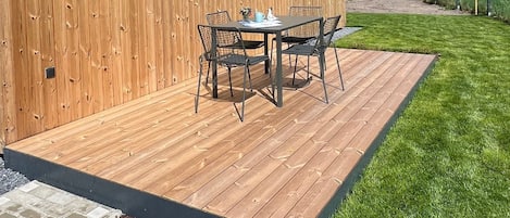 A wooden building with a patio and a table with chairs.