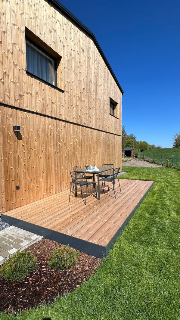 A wooden building with a patio and a table with chairs.