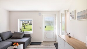 Un soggiorno moderno con un divano grigio, un tavolino in legno e una porta che dà su un balcone.