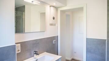 A modern bathroom with a white sink, a mirror, and a shower.