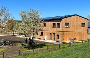 A modern building with a wooden facade, a flat roof, and a small outdoor seating area.