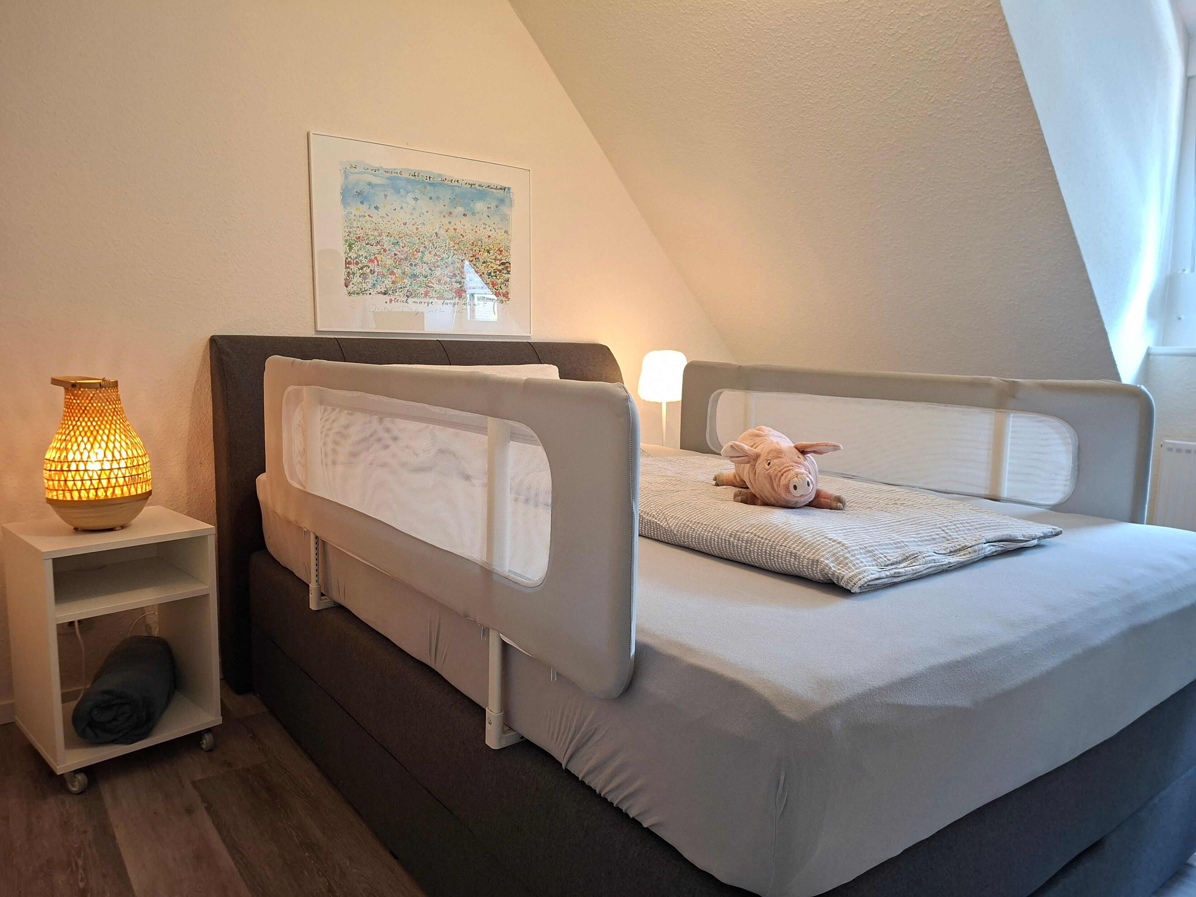 Une chambre avec un lit superposé, une lampe de chevet, un tableau encadré et un jouet en peluche sur le lit.