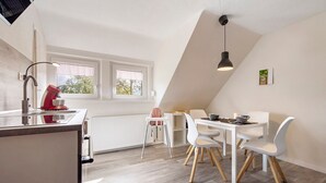 Eine moderne Küche mit Essbereich, weißen Wänden und einer schrägen Decke.