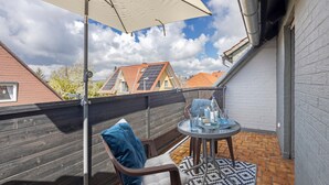 Ein Balkon mit Tisch, Stühlen und einem großen Sonnenschirm.