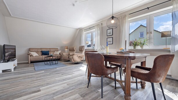 Ein modernes Wohnzimmer mit Essbereich, Holzboden, einer Sofagarnitur und einem Esstisch mit Stühlen.