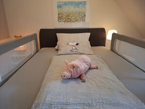 Un llit individual amb un edredó estampat, un coixí amb un personatge de dibuix animat i un quadre penjat a la paret.