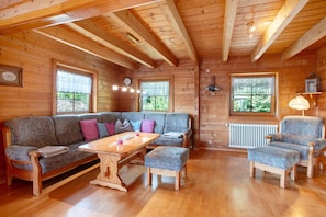 A wooden cabin interior with a sofa, armchairs, a table, and a clock. - Holiday Home 'Ferienhaus Sankt Peter' with Mountain View, Private Terrace and Wi-Fi (Dachsberg)