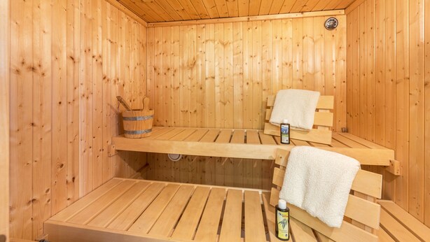 Eine Holzsauna mit Bänken, einem Eimer und einer Ölflasche.