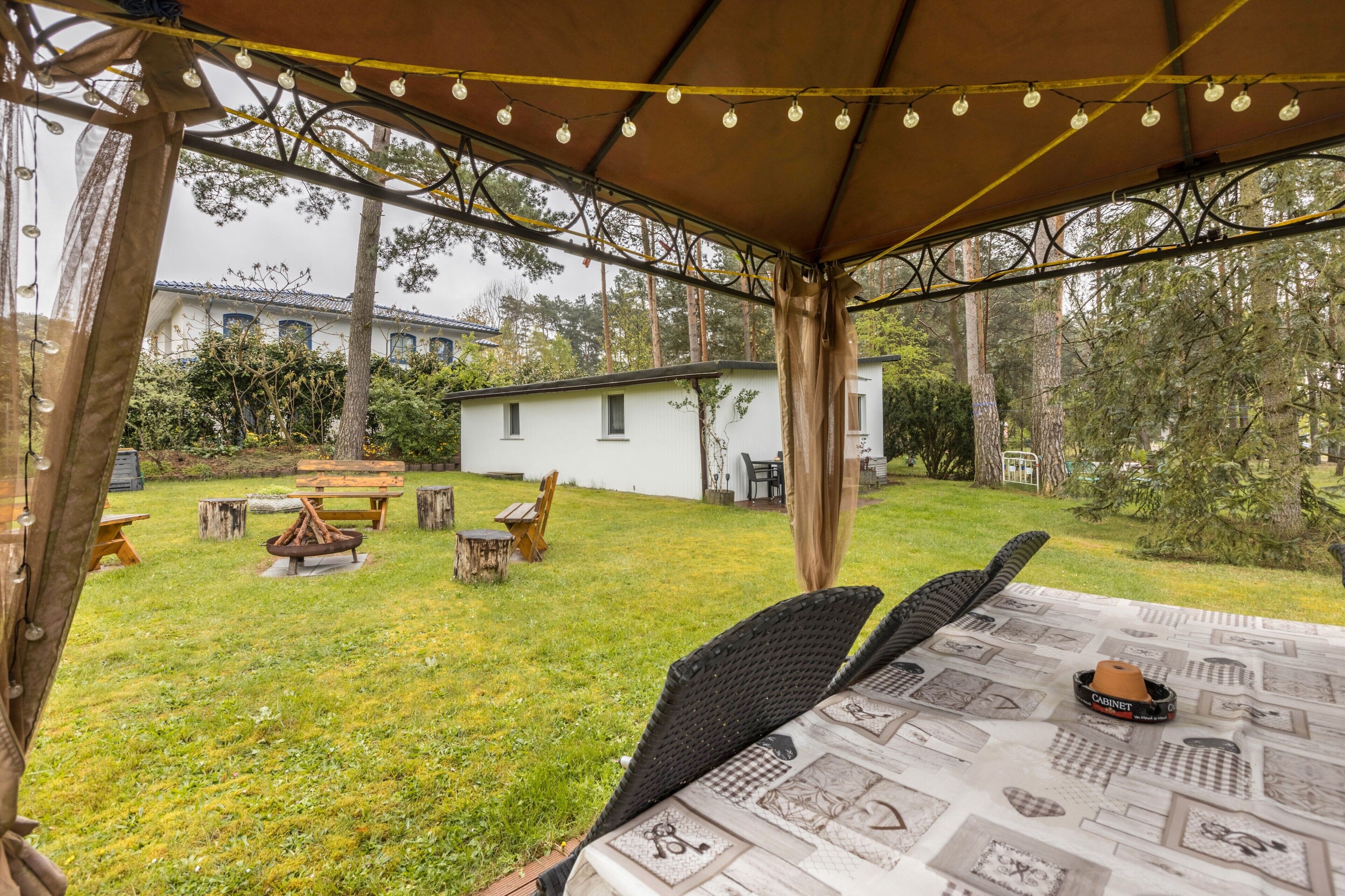 En uteplats med ett bord, stolar och en eldstad.