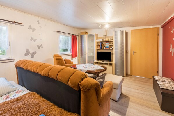 A cozy room with a sofa, a small table, a TV, and a wardrobe.