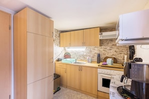 A compact kitchen with wooden cabinets, a sink, a stove, and a coffee maker.