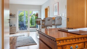 A modern kitchen with a wooden countertop, a dining area with chairs, and a sliding glass door leading to a patio. - Apartment 'Akazie' with Private Terrace and Wi-Fi (Löhne)