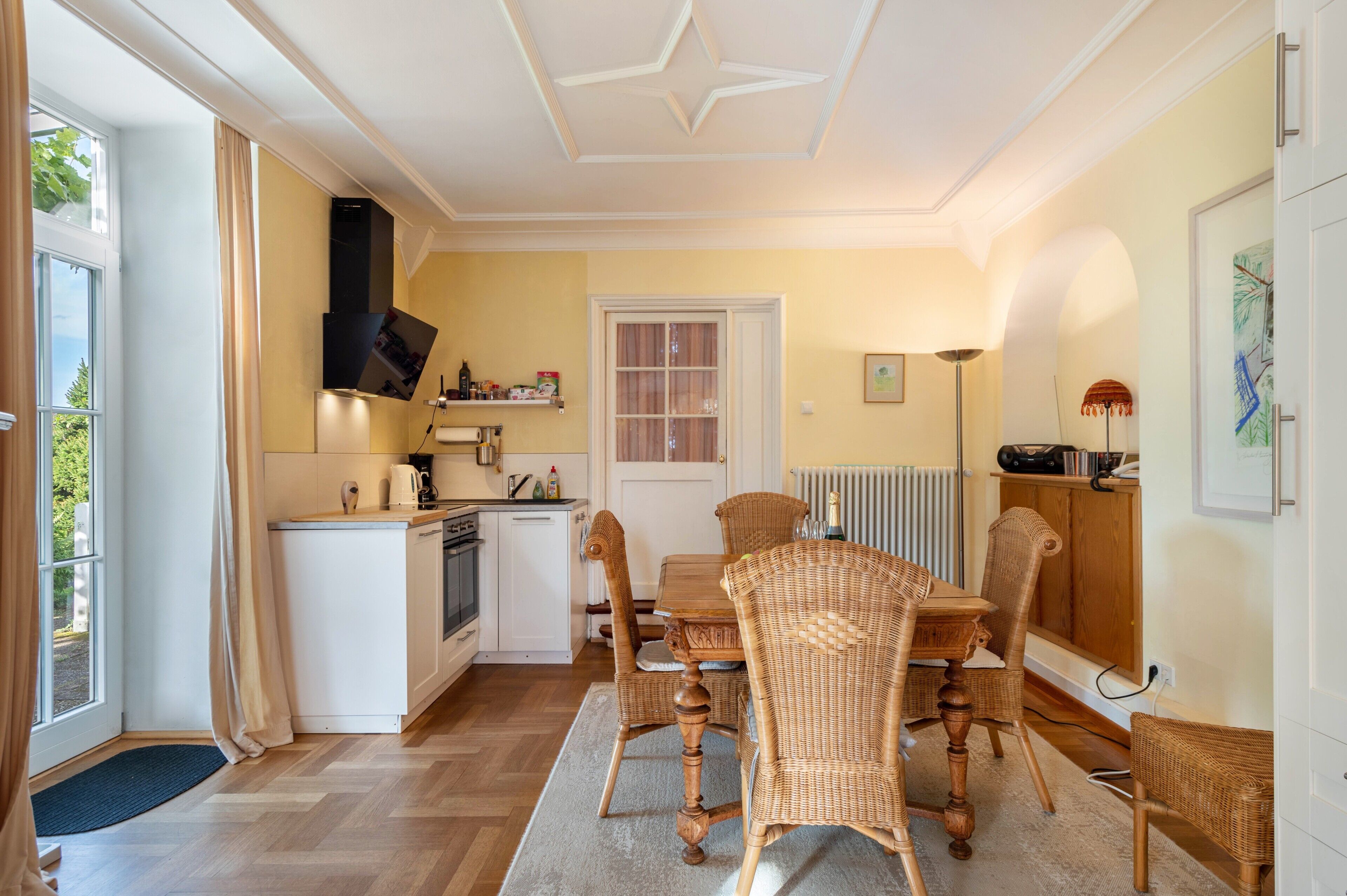 A compact kitchen with a dining area, a built-in stove, and a window with curtains.