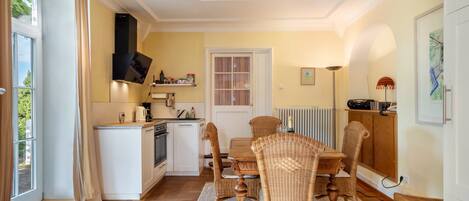 A compact kitchen with a dining area, a built-in stove, and a window with curtains.