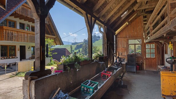 Un edificio rústico de madera con un balcón, vigas de madera y vistas al campo.