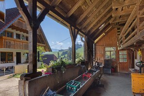A rustic wooden building with a balcony, wooden beams, and a view of the countryside.