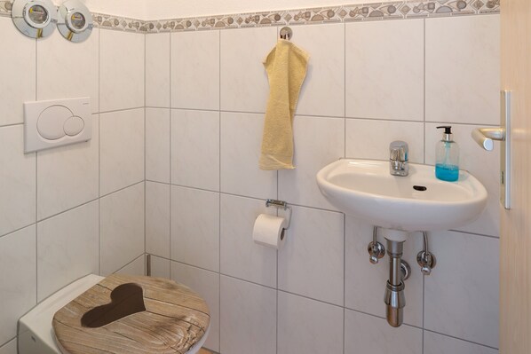 A bathroom with a toilet, a sink, a towel hanging on a rack, and a toilet paper holder.