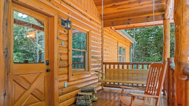 A wooden cabin with a porch, a rocking chair, and a door with a window.