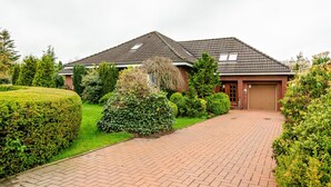 Ein Wohnhaus mit gepflasterter Auffahrt, Garage und gepflegtem Garten.