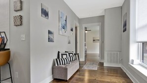 A hallway with a grey sofa, patterned cushions, and artwork on the walls. - *Sleeps 4* Downtown USA ~ Walkable Dickson Apt (Dickson)