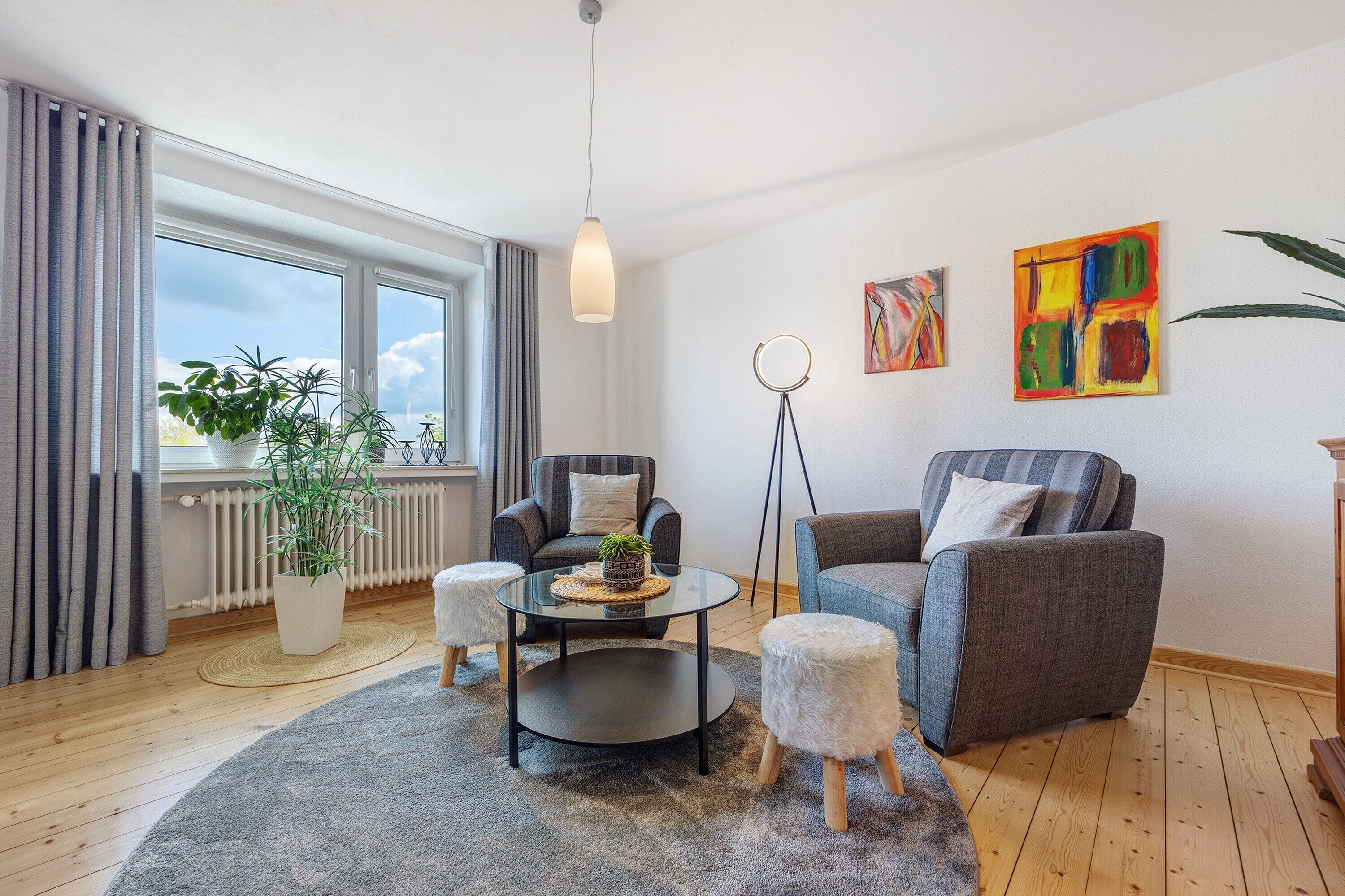 Uma sala de estar moderna com sofá, poltrona, mesa de centro e um vaso de plantas.