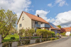 Une maison d’habitation avec un toit en pente, un garage apparent et un petit balcon.