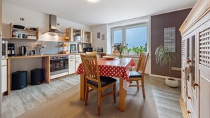 A modern kitchen with a dining table, chairs, and a window. - Apartment 'Weserberglandblumen' with Mountain View, Private Garden and Wi-Fi (Bad Pyrmont)