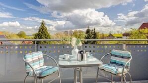 A balcony with two chairs, a table, a vase, and a coffee pot. - Apartment 'Weserberglandblumen' with Mountain View, Private Garden and Wi-Fi (Bad Pyrmont)