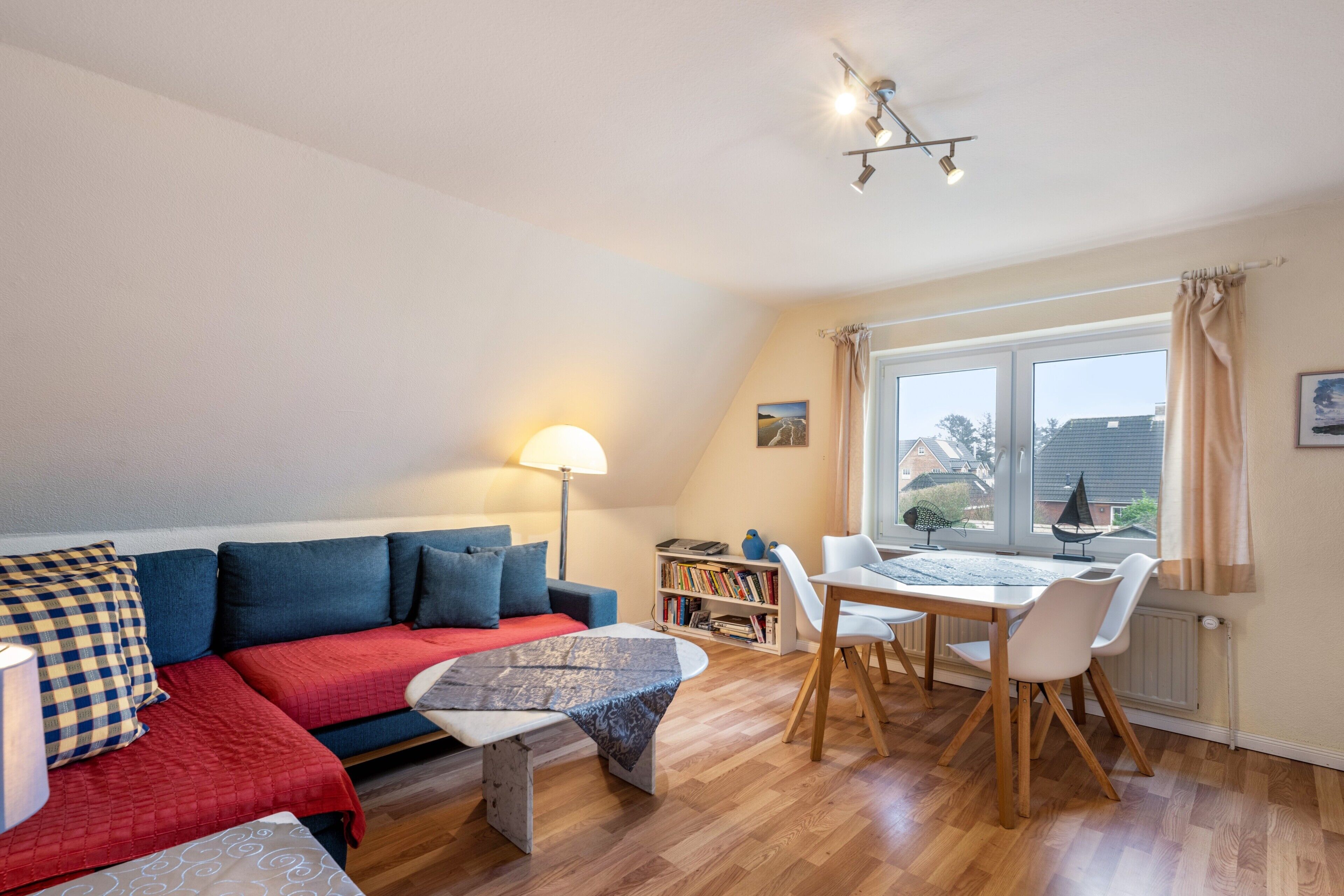 Una sala de estar acogedora con un sofá, una mesa de comedor y una estantería.