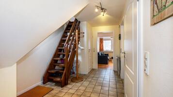 A staircase leading to a landing, a hallway with a tiled floor, and a door leading to another room.
