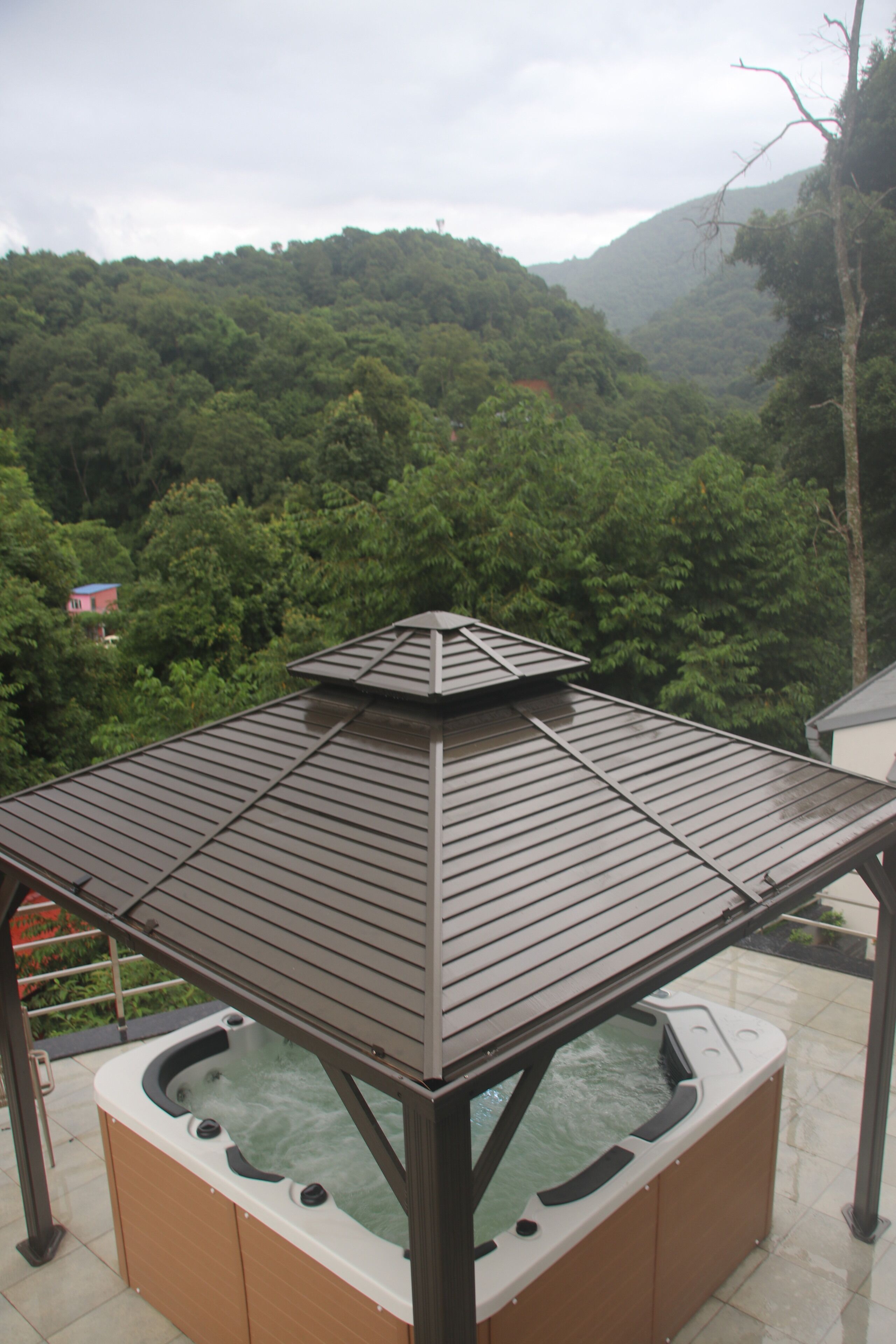 Un jacuzzi con una terraza de madera y vistas a una montaña boscosa.
