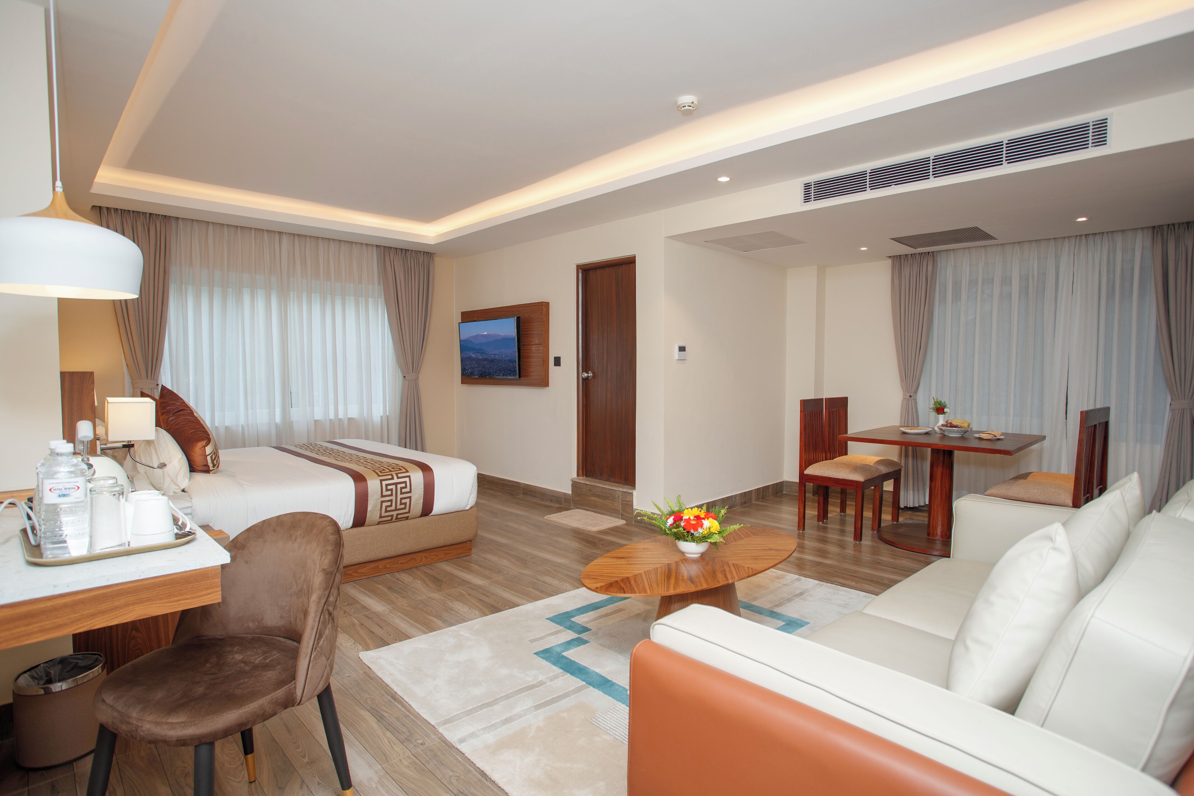 Una habitación de hotel con cama, sofá, mesa de comedor y estación de café.