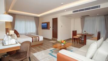 Una habitación de hotel con cama, sofá, mesa de comedor y estación de café.