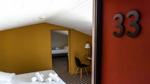 Ett hotellrum med en säng, ett skrivbord, en stol och siffran 33 på väggen.