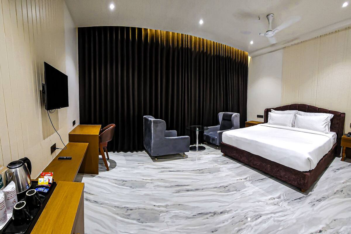 Una habitación de hotel con una cama grande, un escritorio con una silla, un televisor y un minibar.