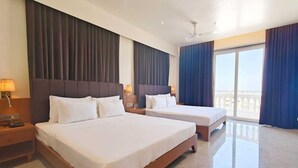 A hotel room with two beds, a balcony, and a ceiling fan. - Hotel S Crown Somnath  (Veraval)