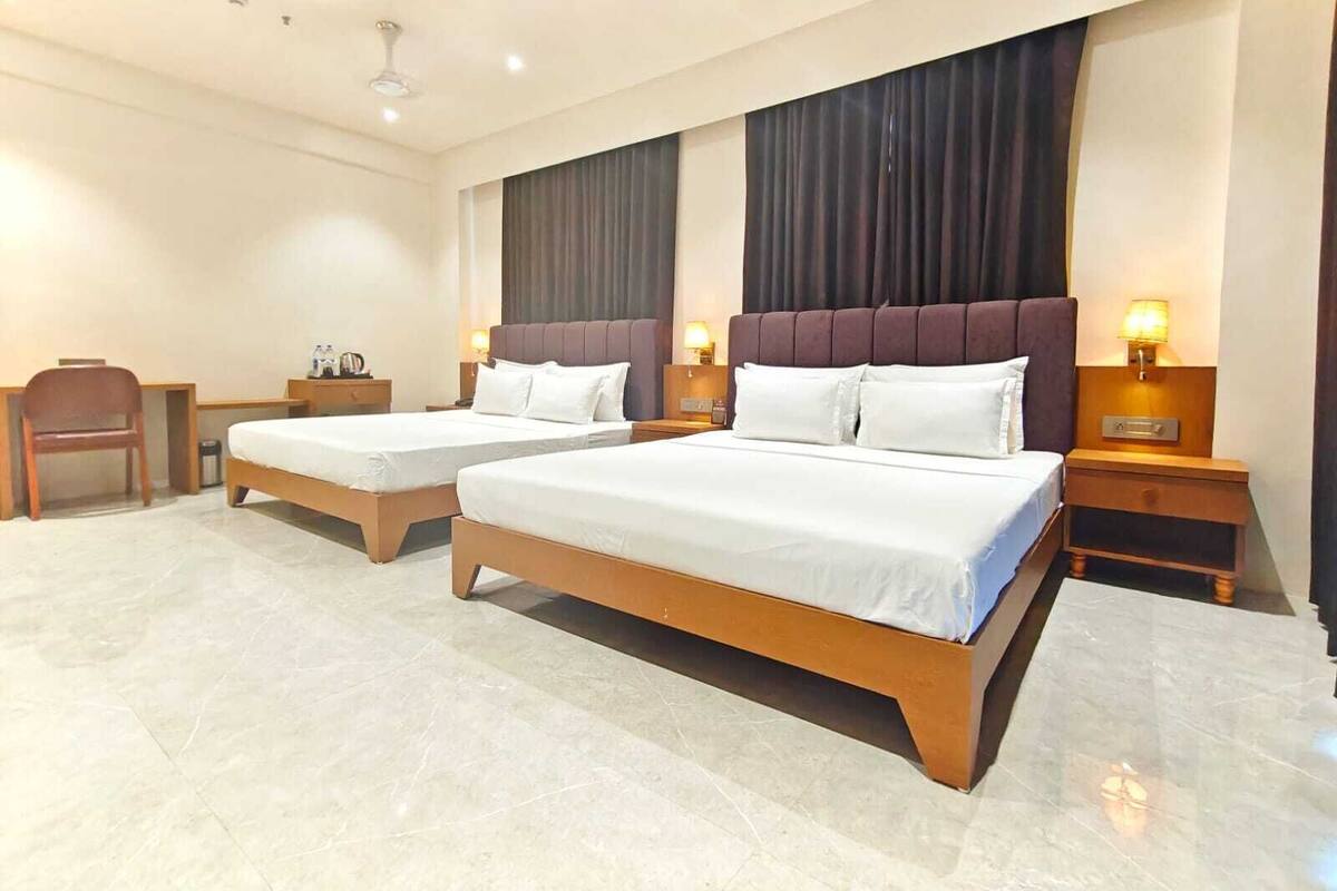 Habitación de hotel con dos camas individuales, un escritorio y una silla.