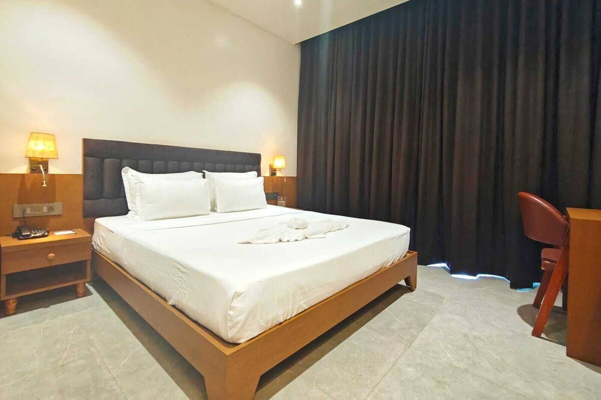 Habitación de hotel con una cama grande, dos mesitas de noche, un escritorio y una silla.