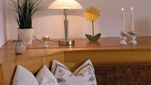 Una mesa de madera con una lámpara, una planta en maceta, un candelabro con velas y almohadones decorativos.