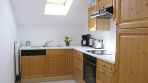 Una cocina compacta con muebles de madera, lavavajillas, estufa y lavamanos.