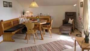 Un salón acogedor con un banco de madera, una mesa de comedor redonda y un sillón cómodo.
