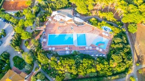 An aerial view of a resort with a large swimming pool, surrounded by lush greenery and a well-maintained landscape. - Villetta Large Morellino 6 pax (Piombino)