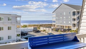 A view from a balcony overlooking a beach, with a building featuring multiple balconies and a parking area in the foreground. - Relaxing Oceanview 2BR Condo in North Myrtle Beach (North Myrtle Beach)