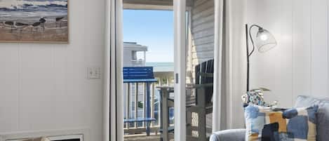 Une pièce avec vue sur la plage, un banc bleu, un coussin à motifs et une lampe.