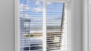 A window with horizontal blinds, a white frame, and a view of buildings and a clear sky. - Relaxing Oceanview 2BR Condo in North Myrtle Beach (North Myrtle Beach)