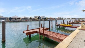 Un muelle frente al agua con pasarelas de madera y un barco amarillo.